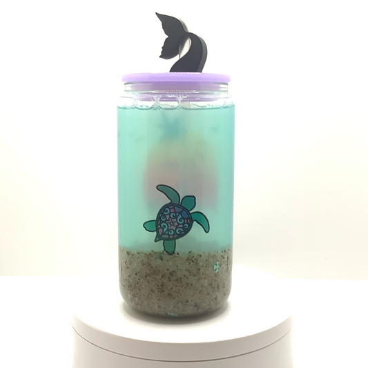 Backside of clear glass can with a turtle design 